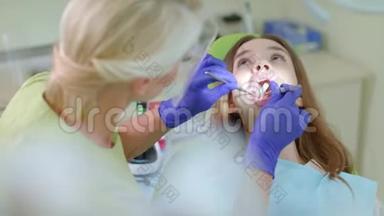牙疼的病人坐在牙医椅上。 为女孩工作的牙医
